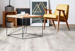 modern flat with a grey leather sofa, grey laminate flooring and a rug